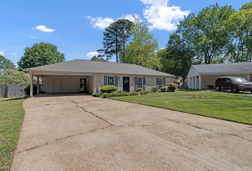Ranch-style house with an attached carport, driveway, brick siding, and roof with shingles