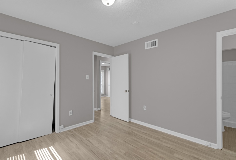 Unfurnished bedroom with light wood-type flooring, a closet, and ensuite bath