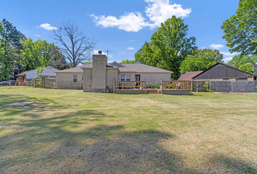 Back of house with a fenced backyard, a chimney, and brick siding