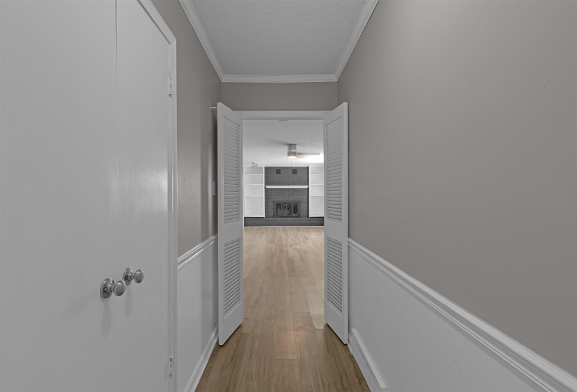 Corridor with ornamental molding, light wood-style flooring, and a textured ceiling