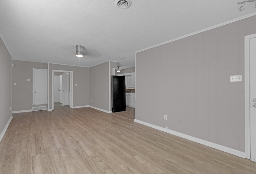 Unfurnished living room featuring crown molding, light wood-style floors, and ceiling fan