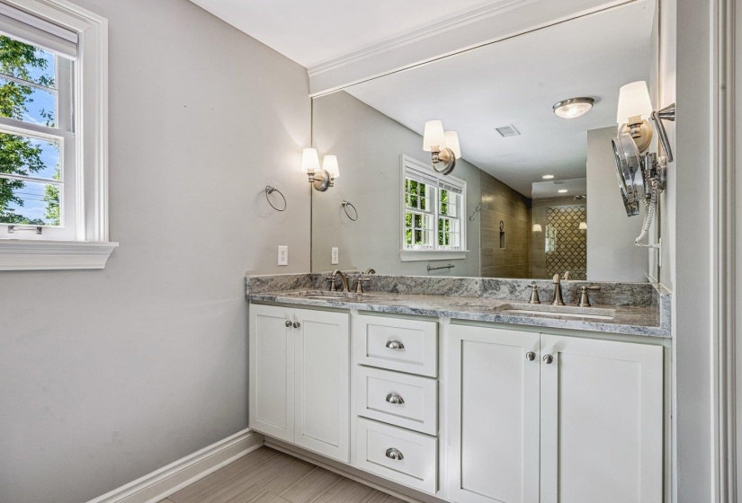 Full bath with double vanity and a shower stall