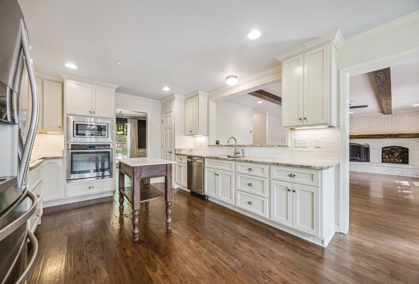 Kitchen with crown molding, stainless steel appliances, light stone countertops, decorative backsplash, and dark wood-style floors