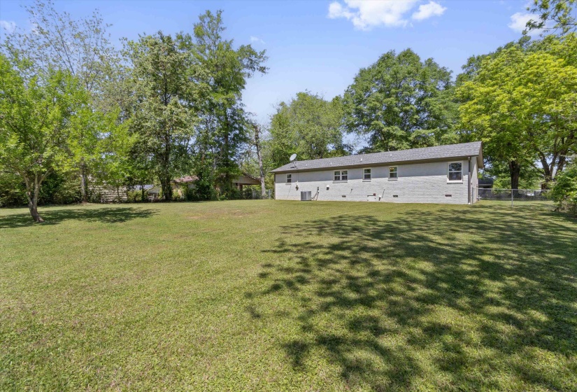 Back of property featuring brick siding, crawl space, and view of wooded area
