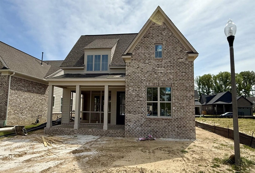 Rear view of house featuring a shingled roof, brick siding, and a patio area