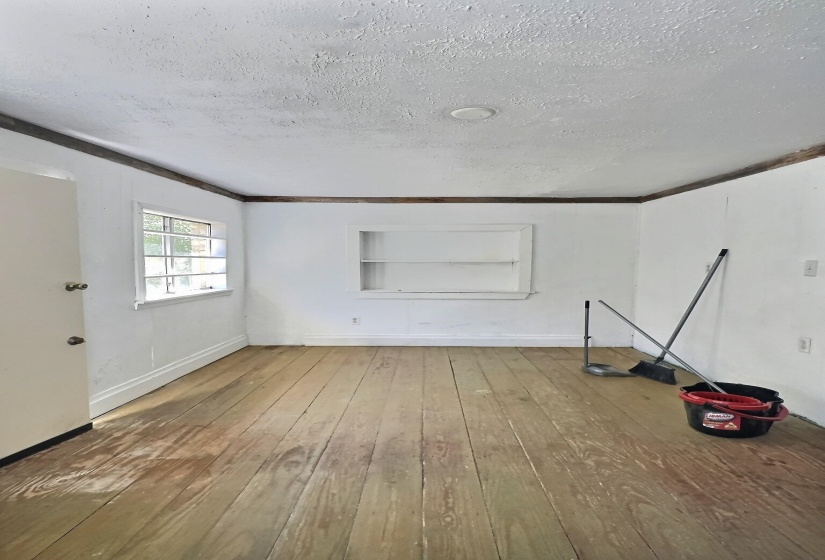 Empty room featuring a textured ceiling, wood-type flooring, and built in features