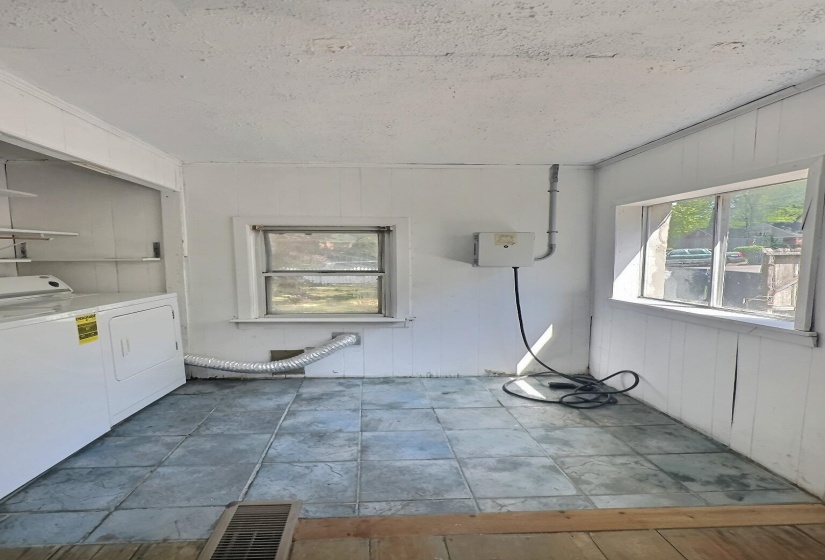 Laundry area featuring wooden walls, a textured ceiling, and washing machine and clothes dryer