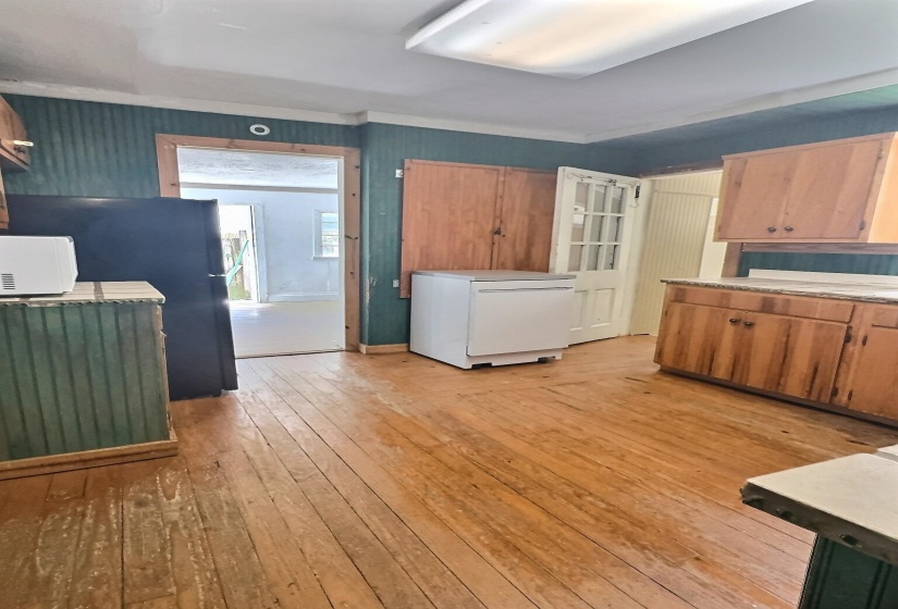 Kitchen with light countertops, white appliances, wood finish cabinets, and light wood-type flooring