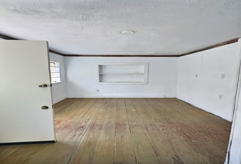 Empty room with built in features, a textured ceiling, and hardwood / wood-style flooring