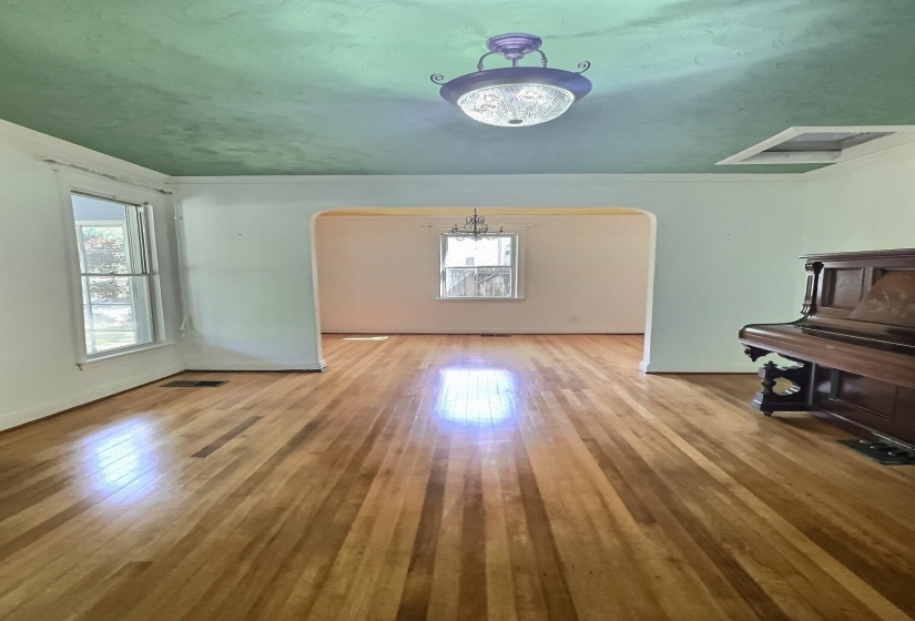 Unfurnished living room with arched walkways, light wood finished floors, and ornamental molding