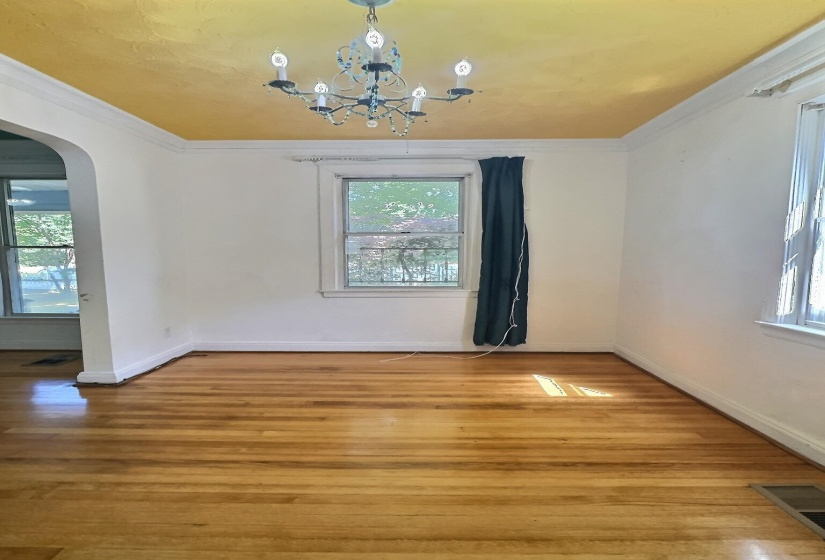 Unfurnished dining area with arched walkways, wood-type flooring, ornamental molding, and suspended lighting