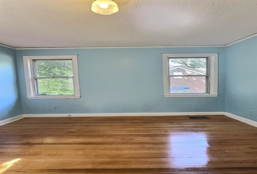 Empty room with dark wood finished floors, ornamental molding, and a textured ceiling