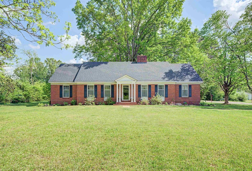 Ranch-style house featuring a front lawn, brick siding, and a chimney