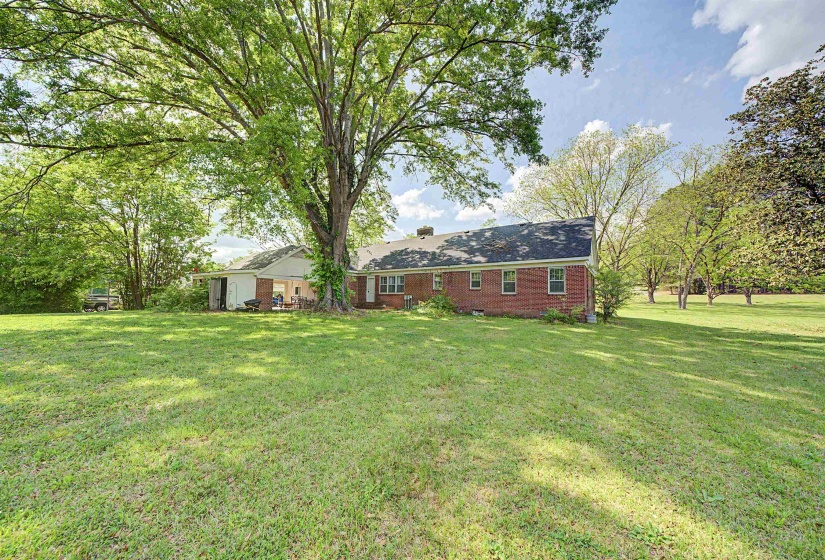 Rear view of property featuring a yard, brick siding, and crawl space