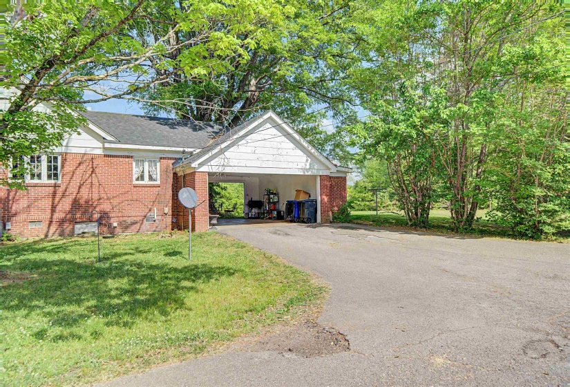 View of front of home with brick siding, a front yard, driveway, and a shingled roof