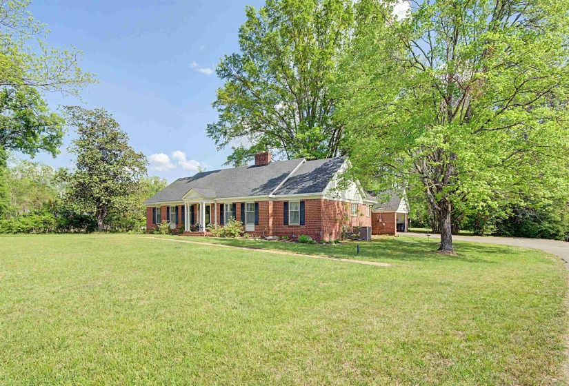 View of front of home with a front yard, brick siding, a chimney, and a shingled roof