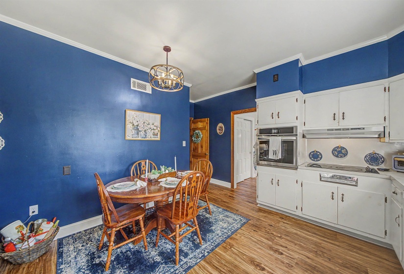 Dining room featuring light wood-style flooring, hanging lights, and crown molding