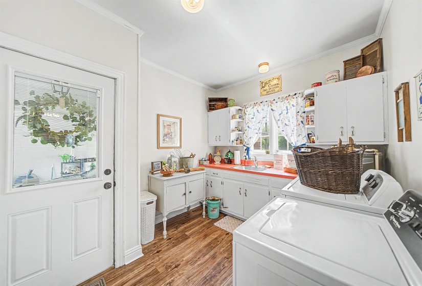 Laundry room featuring cabinet space, wood finished floors, washing machine and clothes dryer, and crown molding
