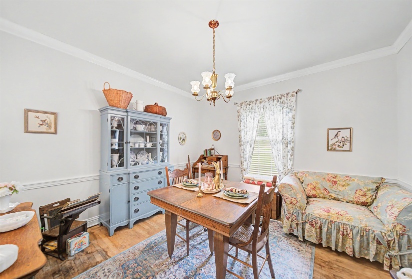 Dining room featuring light wood-style floors, hanging lights, and ornamental molding