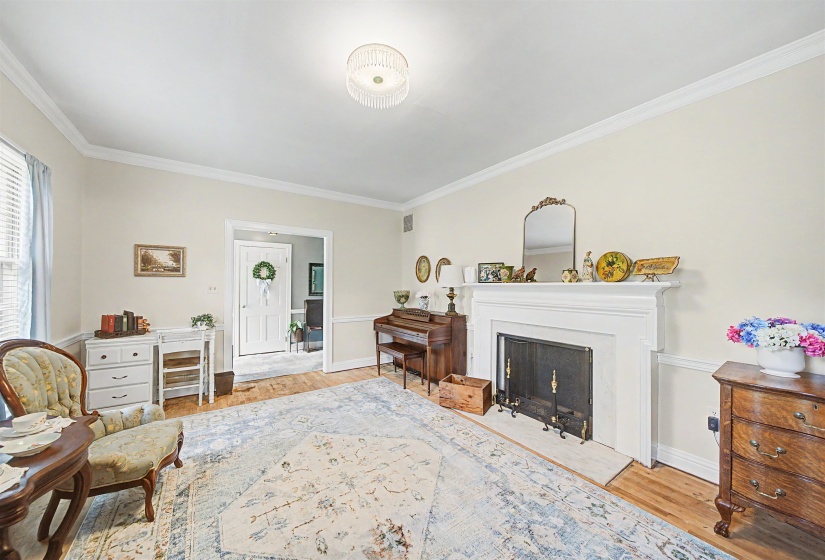 Living area with light wood finished floors, ornamental molding, and a fireplace with flush hearth