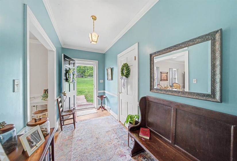 Entryway with ornamental molding and wood finished floors