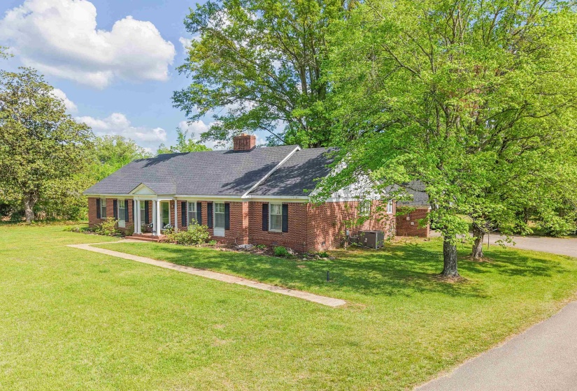 View of front of house featuring a front lawn, brick siding, a chimney, and a porch