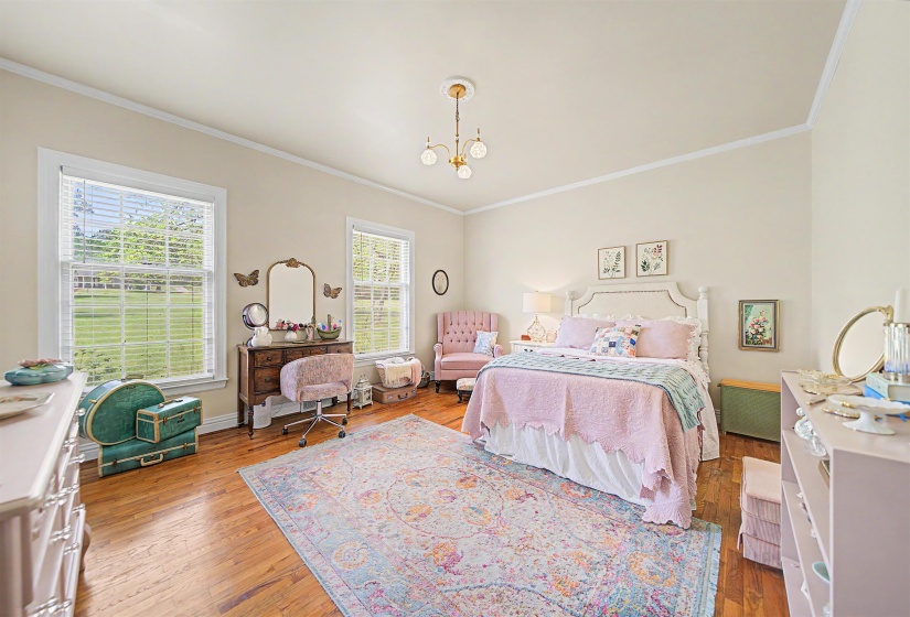 Bedroom with light wood finished floors, ornamental molding, and a chandelier