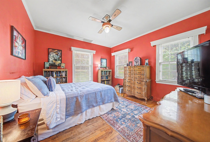 Bedroom featuring multiple windows, wood-type flooring, ceiling fan, and ornamental molding