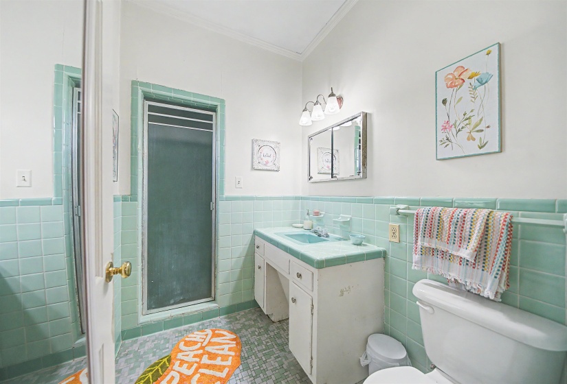 Bathroom with a stall shower, vanity, a wainscoted wall, crown molding, and tile walls