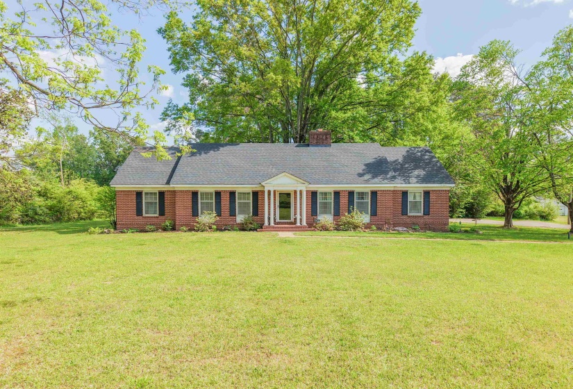 Ranch-style home with a front yard, brick siding, and a chimney