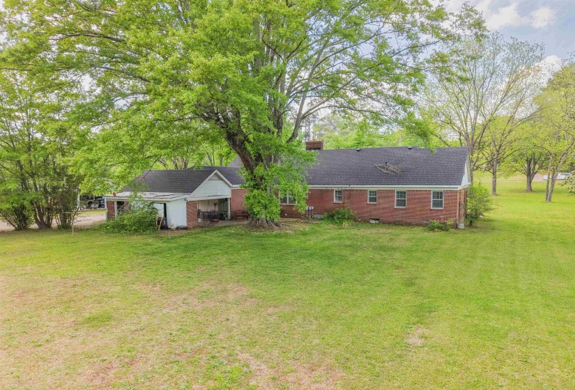 Rear view of property featuring a yard, brick siding, a chimney, crawl space, and roof with shingles