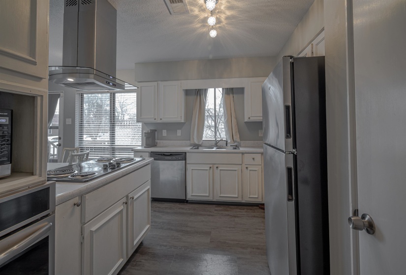Kitchen featuring white cabinetry, appliances with stainless steel finishes, and island range hood