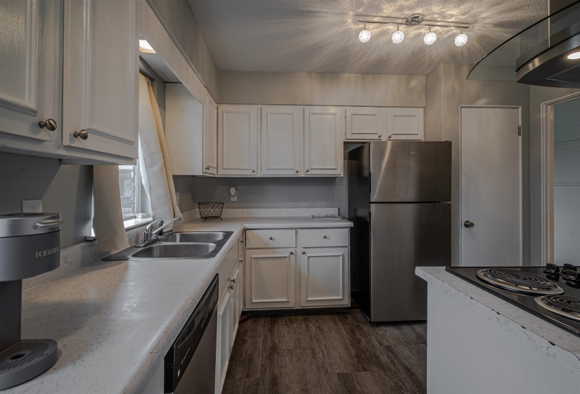 Kitchen with appliances with stainless steel finishes, dark hardwood / wood-style floors, ventilation hood, sink, and white cabinets