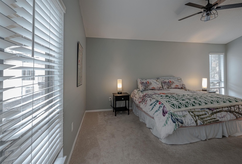 Carpeted bedroom with vaulted ceiling and ceiling fan