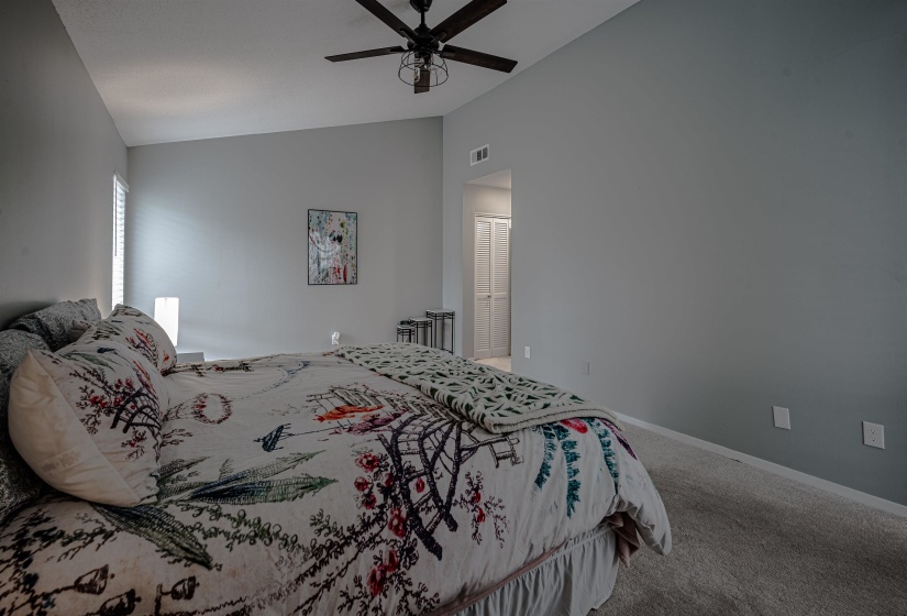 Carpeted bedroom featuring lofted ceiling and ceiling fan