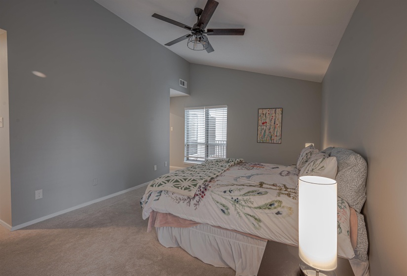 Bedroom with vaulted ceiling, ceiling fan, and carpet floors
