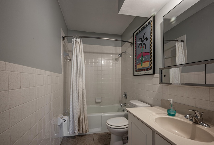 Full bathroom with tile patterned flooring, tile walls, shower / tub combo, and toilet