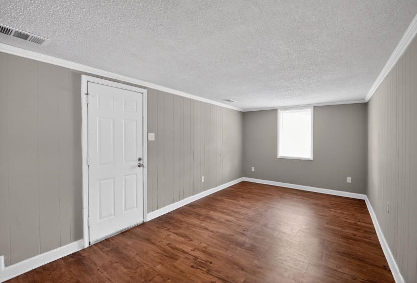Unfurnished room featuring crown molding, dark wood-style floors, and a textured ceiling