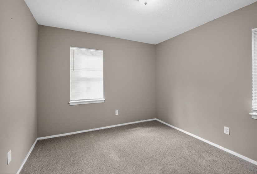 Empty room with light carpet and a textured ceiling