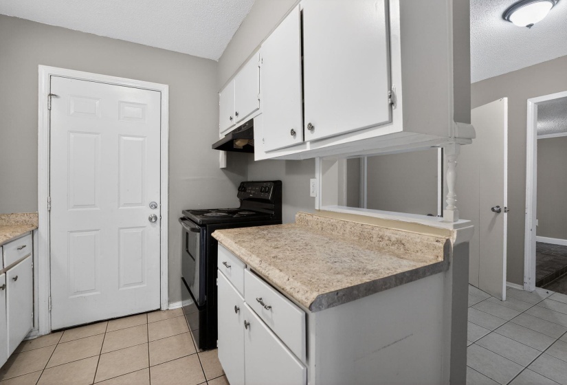 Kitchen with white cabinets, black range with electric cooktop, light countertops, a textured ceiling, and light tile patterned floors