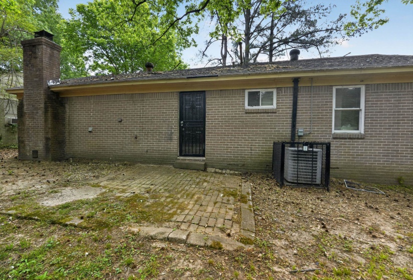 Back of house featuring brick siding and a chimney