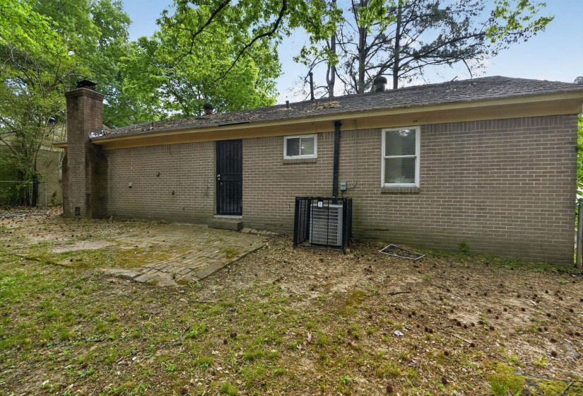 Rear view of property featuring a patio area, brick siding, and a chimney