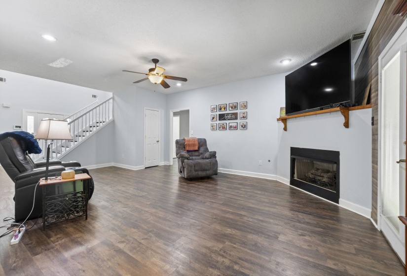 Living room featuring a fireplace, ceiling fan, dark wood-type flooring, and recessed lighting