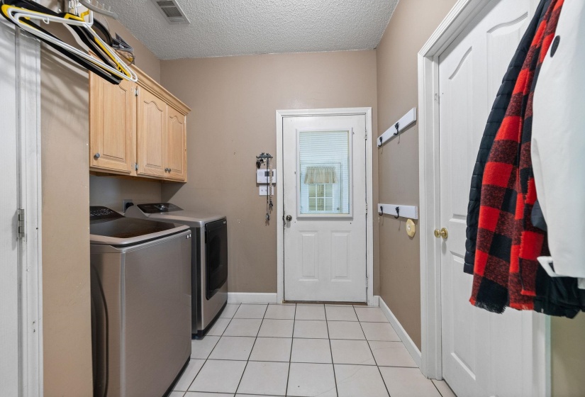 Laundry area featuring a textured ceiling, cabinet space, washer and clothes dryer, and light tile patterned floors