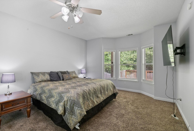 Bedroom with dark colored carpet, a textured ceiling, and ceiling fan