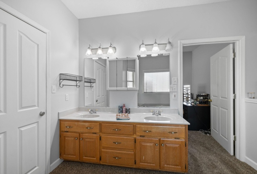 Dual vanity with wood cabinetry, integrated sinks, white countertops, and chrome fixtures