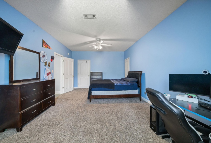 Spacious room featuring vaulted ceilings, neutral-toned carpeting, and a ceiling fan