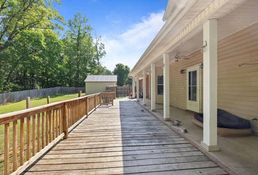 Expansive wood deck and ramp along the rear facade, featuring a covered patio area with support columns and ceiling fans