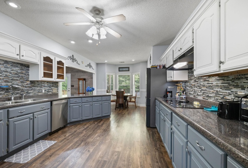 Two tone kitchen with a ceiling fan, decorative backsplash, dark wood-type flooring, two tone cabinetry, and stainless steel appliances