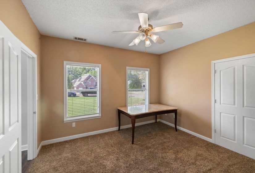 Unfurnished office featuring ceiling fan, dark carpet, and a textured ceiling